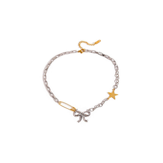 Mixed metal bow and star necklace with safety pin and playful trims.